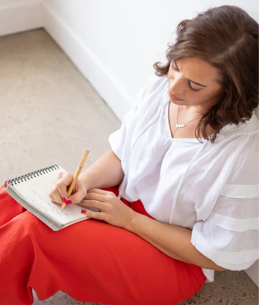 Halle Simpson writing in a notebook during a reflective leadership coaching exercise.
